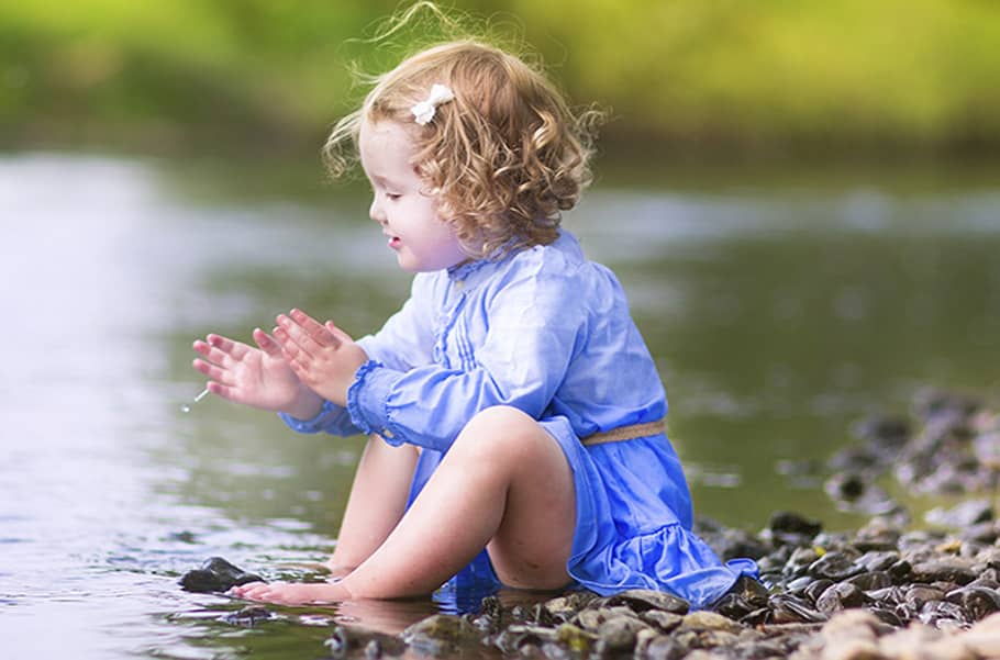 Bambina seduta vicino all’acqua